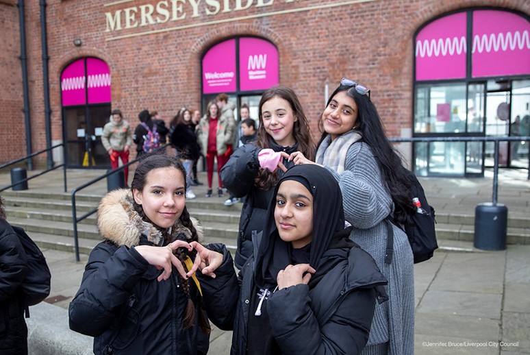 Four teenage girls making heart shapes out of their fingers