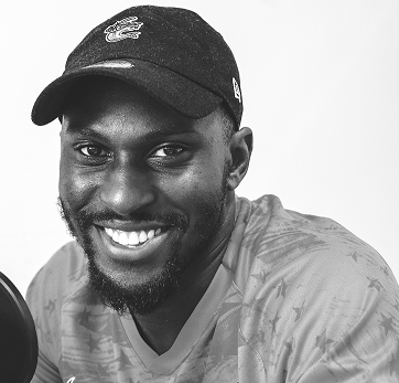 A black man wearing a base ball cap smiling at the camera