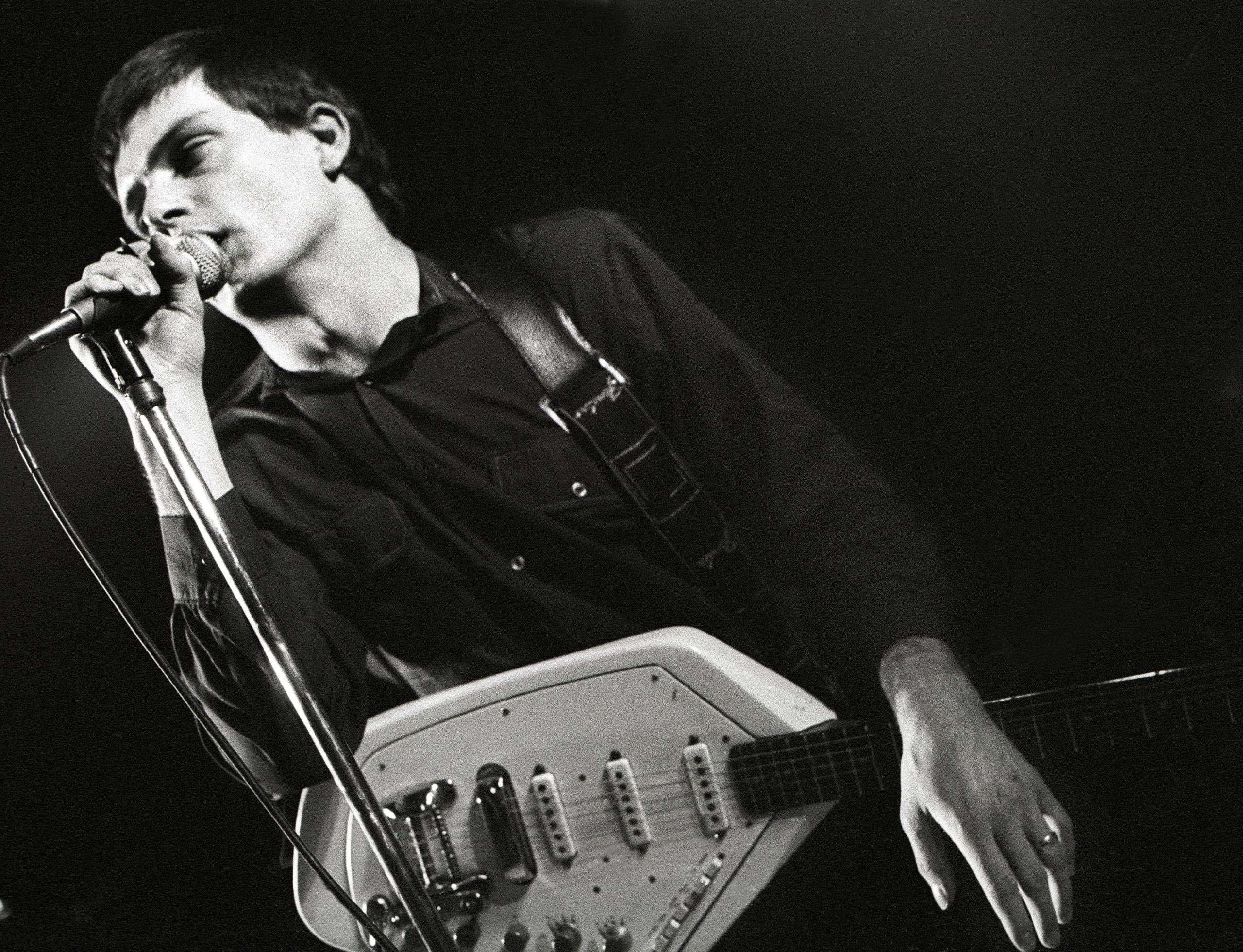 A man with a guitar singing in a microphone