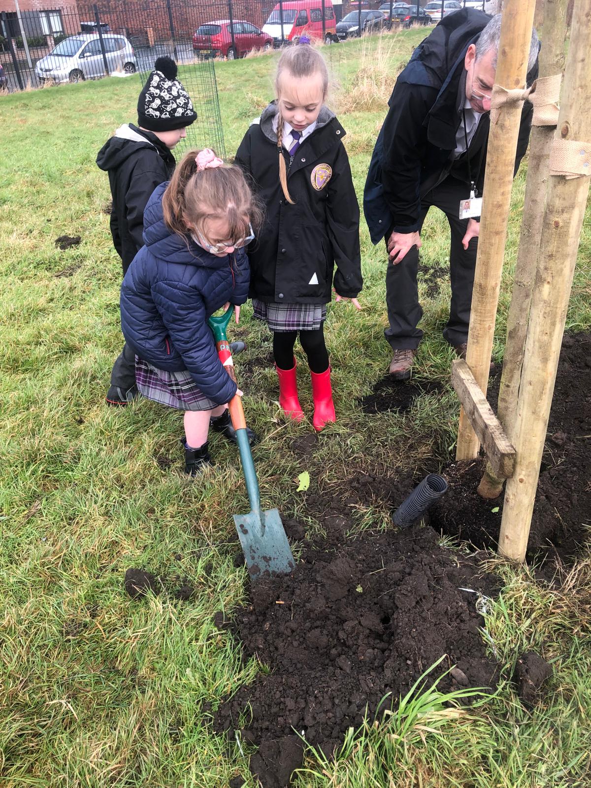 Primary school pupils planting a tree
