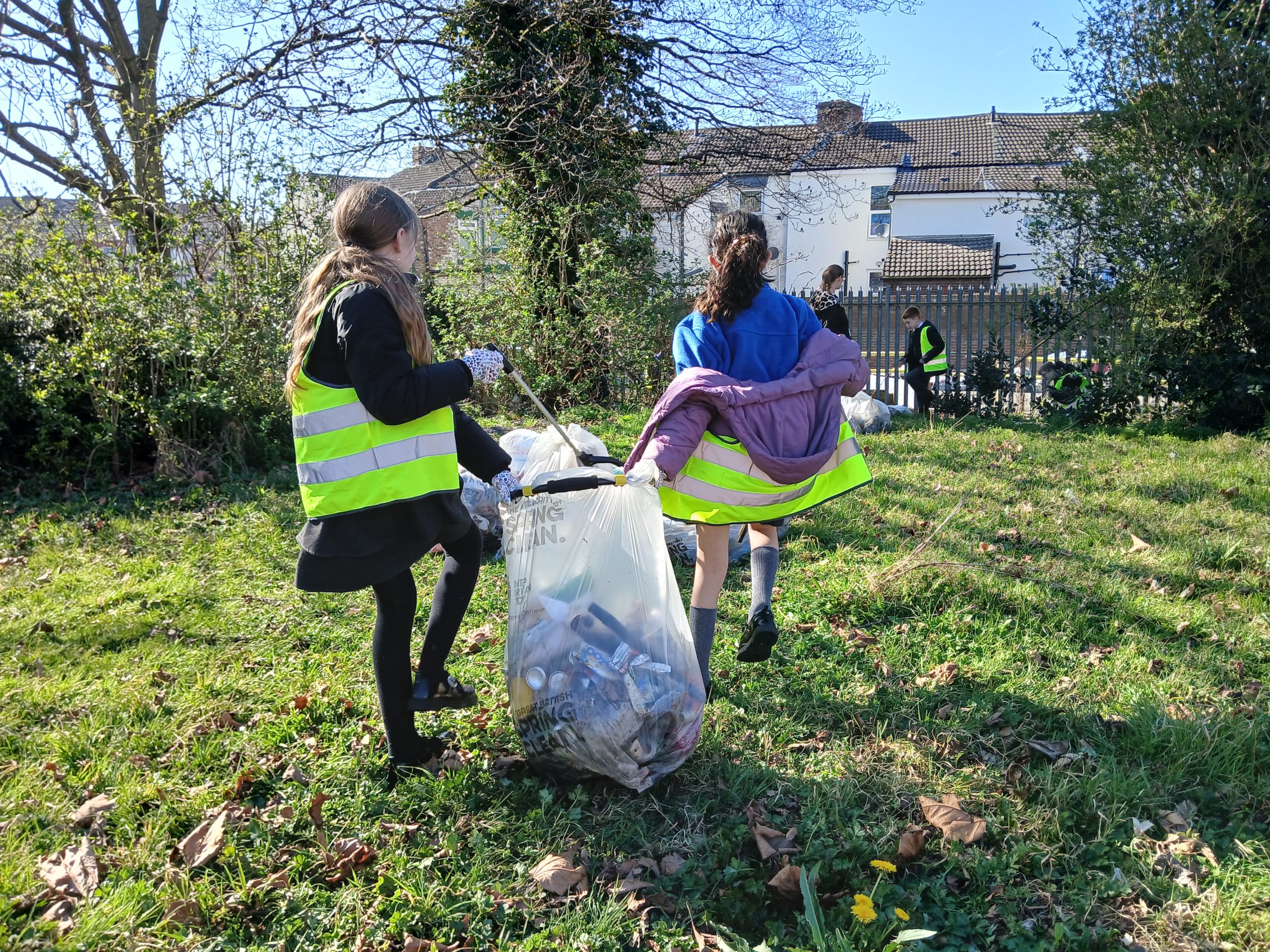 Two girls from Gwladys Street Primary holding a litter bag