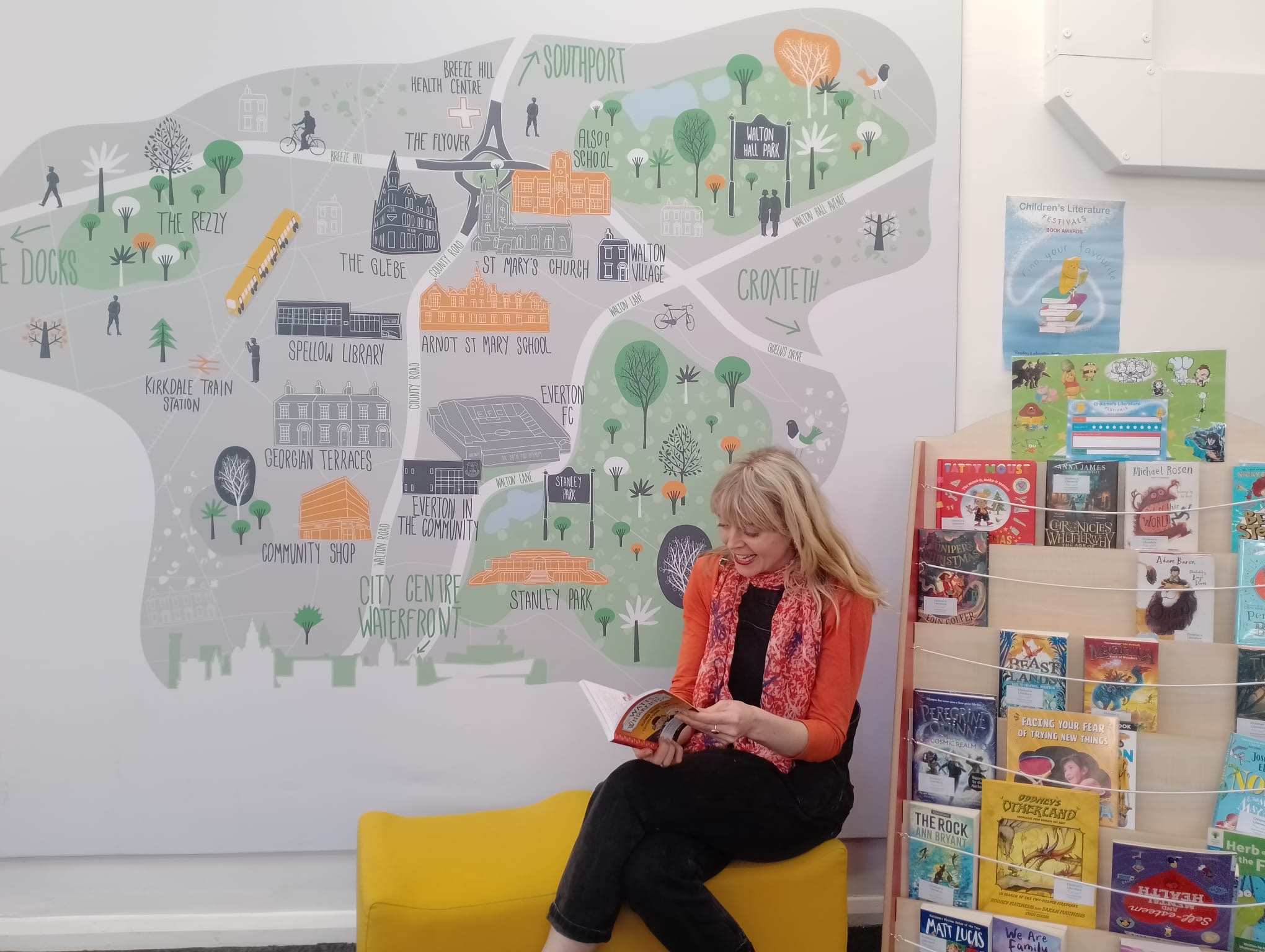 A woman sat down reading in front of a map