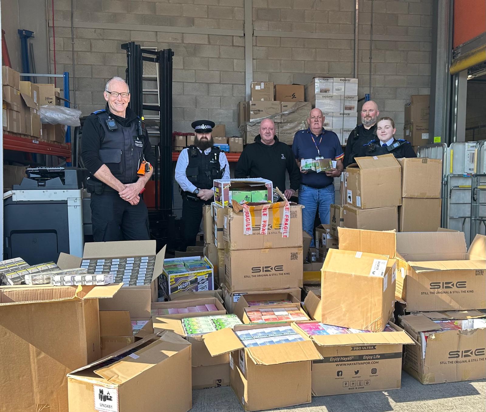 Staff from Merseyside Police and Trading Standards stood behind boxes of seized vapes and cigarettes
