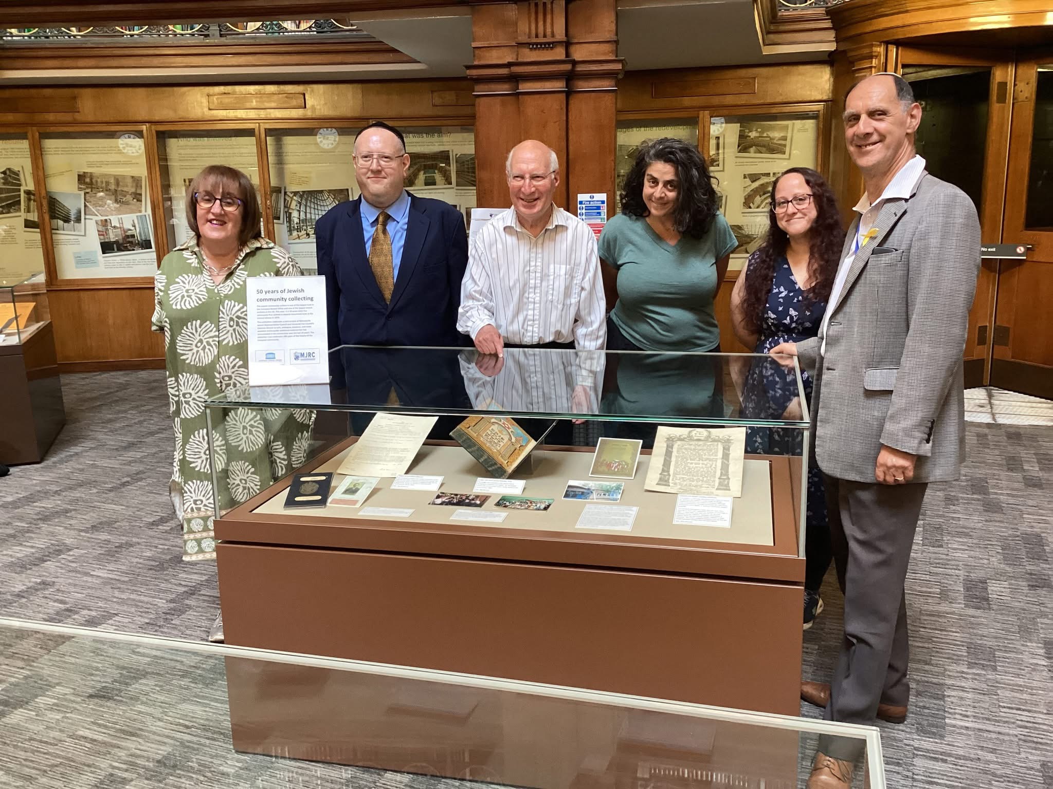 Group of 6 people stood behind a glass exhibition case