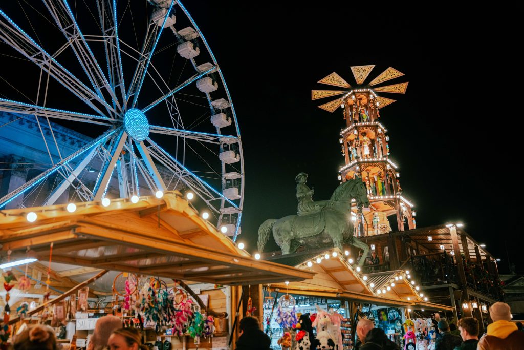 Outdoor Christmas market stalls with a ferris wheel in the background