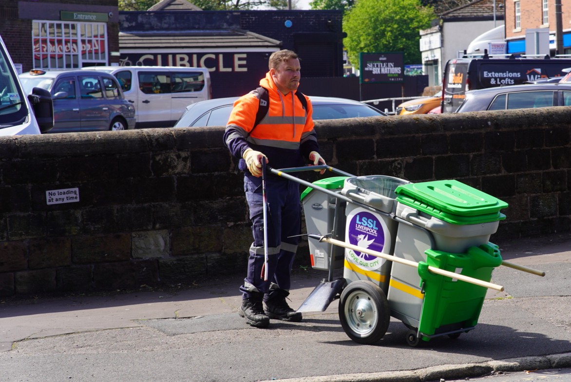 A person pushing a portable waste collection unit